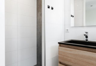 Modern bathroom in a tiny house at The Kremmer, Netherlands, featuring wood vanity and walk-in shower.