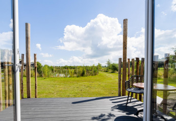 Vista desde una tiny house con terraza en The Kremmer, Países Bajos; puertas abiertas a un jardín verde.