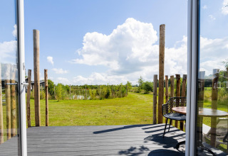 View from a tiny house with decking at The Kremmer in the Netherlands, open doors to a grassy garden.