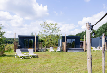 Tiny house con terrazze e lettini prendisole sull'erba a The Kremmer, Paesi Bassi, in una giornata di sole.