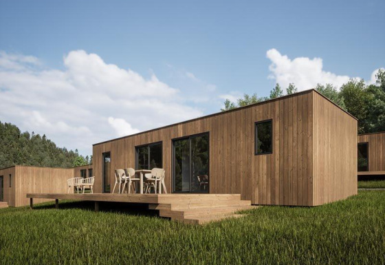 Eco Lodge con rivestimento in legno, terrazza e zona pranzo esterna immersa in un ambiente naturale verde.