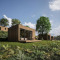 Moderne houten lodges met grote ramen bij Cocoon de l'Ourthe, omgeven door gras en bomen in de natuur.