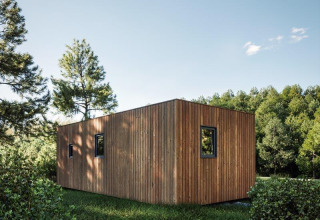 Eco Lodge bij Hameau de l'Ourthe in België, moderne houten lodge omgeven door bomen en groen gras.