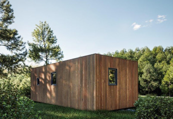 Eco Lodge bij Hameau de l'Ourthe in België, moderne houten lodge omgeven door bomen en groen gras.