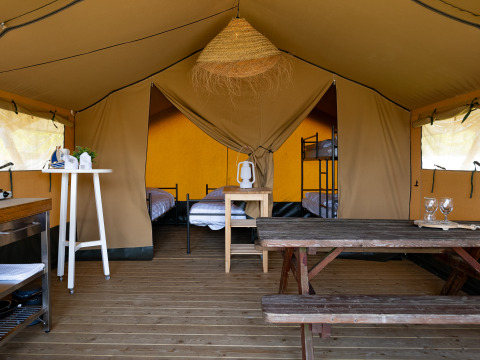 Binnenkant van een safaritent bij Marina Heeg, Nederland, met houten vloer, tafel en stapelbedden.