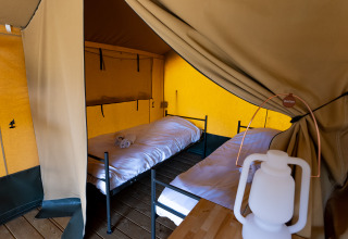 Innenansicht des Safari-Zeltes Heeg in der Marina Heeg, Niederlande, mit zwei Betten und einer Lampe.