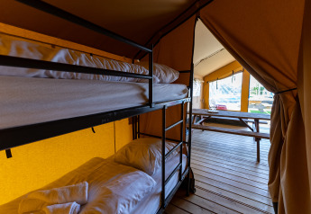 Interno di tenda safari con letti a castello e tavolo di legno a Marina Heeg nei Paesi Bassi.