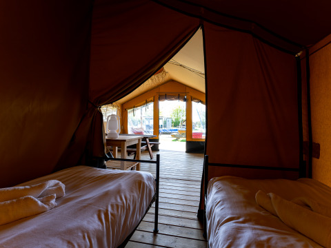Vista interior de la tienda Safari tent Heeg en Marina Heeg, Países Bajos, con dos camas y terraza de madera.