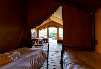 Vista interior de la tienda Safari tent Heeg en Marina Heeg, Países Bajos, con dos camas y terraza de madera.