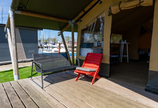Tienda safari Heeg en Marina Heeg, Países Bajos, con terraza, sillas y vistas al puerto deportivo.