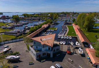Vue aérienne de Houseboat Heeg à Marina Heeg, Pays-Bas, entouré de bateaux et d’une marina animée.