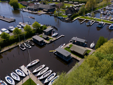 Vista aérea de casas flotantes y barcos en Marina Heeg, Países Bajos, rodeadas de vegetación.