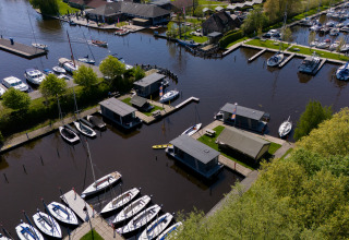 Vue aérienne de péniches et bateaux à la Marina Heeg aux Pays-Bas, entourés de verdure.