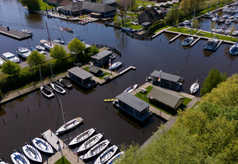 Vista aerea di houseboat e barche alla Marina Heeg nei Paesi Bassi, circondate dal verde.