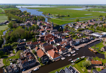 Aerial photo of Houseboat Heeg at Marina Heeg in the Netherlands, surrounded by water, boats, and green fields.