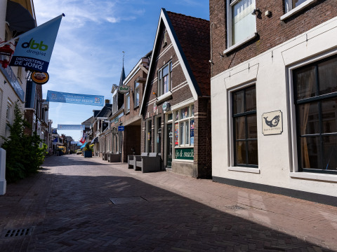 En stille brostensgade med små butikker og skilte i en hollandsk by, fotograferet ved glampingophold.