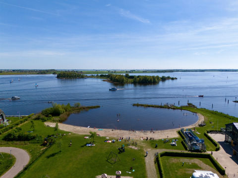 Blick auf Strand und See vom Hausboot Heeg an der Marina Heeg, Niederlande, bei blauem Himmel.