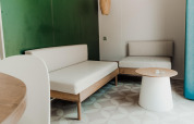 Moderne zithoek in een chalet met lichte meubels, groene accentmuur en een ronde tafel bij het raam.