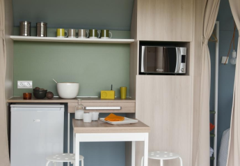 Cocina pequeña y moderna en una tienda Coco Sweet, con microondas, nevera y barra para comer.