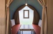 Innenraum eines Coco Sweet Safari-Zeltes mit zwei Bänken, Tisch, Fenster und beigen Vorhängen.