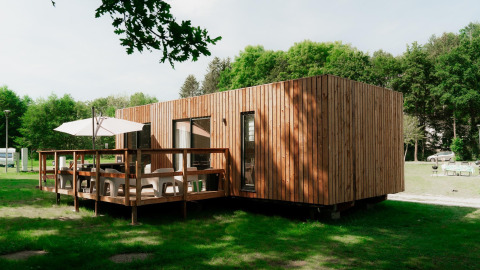 Alojamiento glamping moderno con fachada de madera y terraza, rodeado de naturaleza verde.