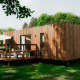 Alojamiento glamping moderno con fachada de madera y terraza, rodeado de naturaleza verde.