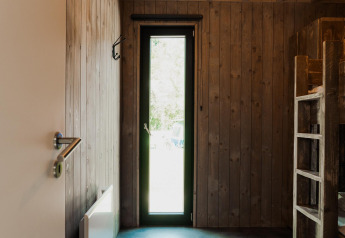 Camera rivestita in legno con letti a castello e stretta porta a vetri, tipica alloggio in stile glamping.