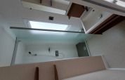 Bagno moderno in alloggio glamping con doccia, lavabo e ampia finestra che lascia entrare la luce.
