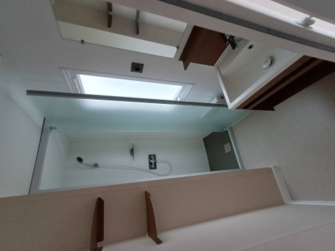 Bagno moderno in alloggio glamping con doccia, lavabo e ampia finestra che lascia entrare la luce.