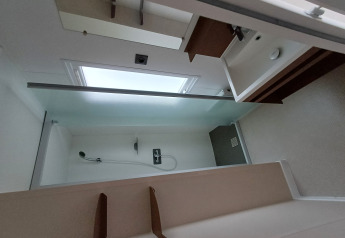 Baño moderno en un alojamiento glamping con ducha, lavabo y gran ventana que deja entrar luz natural.