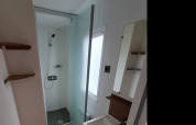 Baño moderno en un alojamiento glamping con ducha, lavabo y gran ventana que deja entrar luz natural.