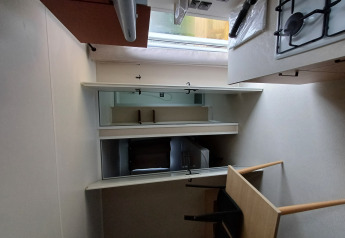 Pequeña cocina en un alojamiento de glamping con estufa de gas, mesa, sillas y espejo de pared.