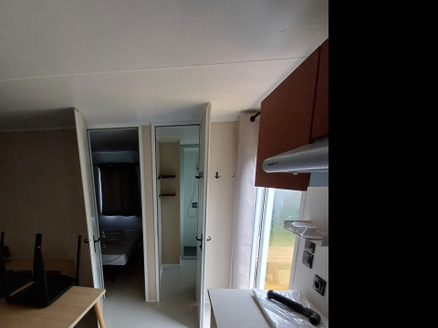 Piccola cucina in una sistemazione glamping con fornello a gas, tavolo, sedie e uno specchio a parete.