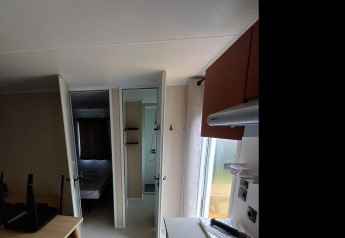 Kleine kitchenette in een glamping-accommodatie met gasfornuis, tafel, stoelen en een wandspiegel.