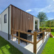 Struttura glamping moderna con terrazza, area salotto all'aperto e vista su un paesaggio verde e naturale.