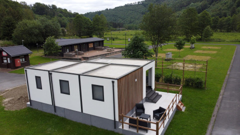 Modernes Glamping-Unterkunft mit Terrasse und Sitzplätzen im Freien in grüner Umgebung.