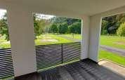 View from a modern glamping accommodation terrace overlooking green grassy areas and trees.
