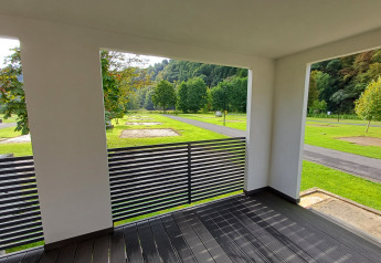 View from a modern glamping accommodation terrace overlooking green grassy areas and trees.