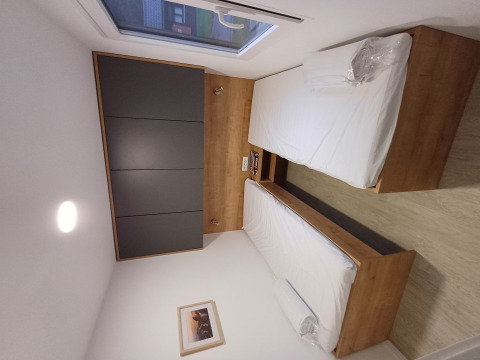 Stanza di glamping moderna con due letti singoli, mobili in legno e una grande finestra luminosa.