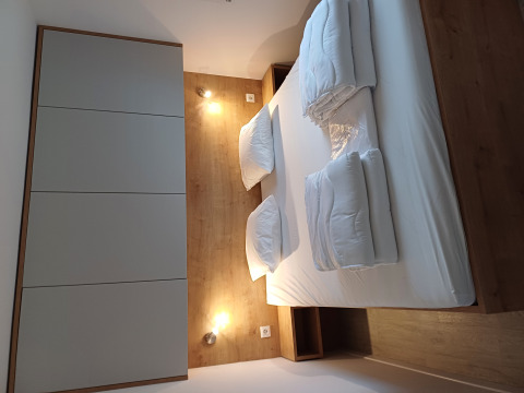 Alloggio glamping moderno con letto matrimoniale, parete in legno, biancheria e illuminazione soffusa.