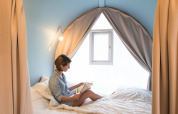 Donna che legge un libro nella tenda safari Coco Sweet al Camping La Colline in Belgio, atmosfera accogliente.