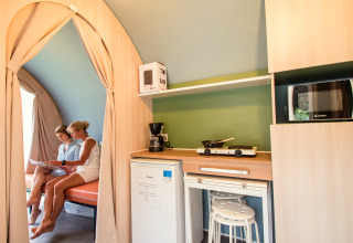 Interieur van de Coco Sweet safaritent op Camping La Colline, België, met twee vrouwen, keuken en zitruimte.