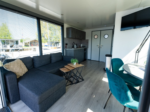 Sala y cocina en el Houseboat Heeg en Marina Heeg, Países Bajos, con muebles modernos y amplios ventanales.