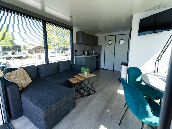 Sala y cocina en el Houseboat Heeg en Marina Heeg, Países Bajos, con muebles modernos y amplios ventanales.