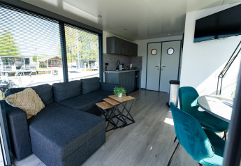 Soggiorno e cucina nella Houseboat Heeg alla Marina Heeg, Paesi Bassi, con arredi moderni e ampie finestre.