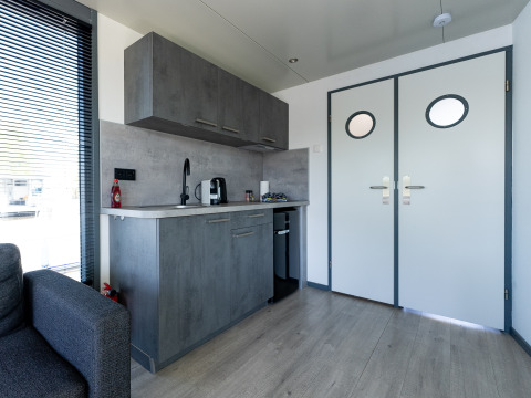 Pequeña cocina moderna en Houseboat Heeg con armarios grises, ubicada en Marina Heeg, Países Bajos.