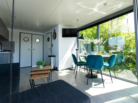 Sala moderna en la casa flotante Houseboat Heeg con grandes ventanas y vistas verdes en Marina Heeg, Países Bajos.