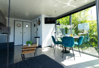 Moderne stue på husbåd Houseboat Heeg med store vinduer og grøn udsigt, beliggende i Nederlandene.