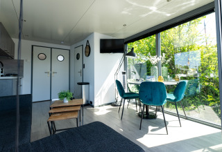 Moderne woonkamer op houseboat Heeg met grote ramen en groen uitzicht, gelegen bij Marina Heeg, Nederland.
