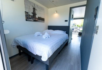 Slaapkamer op Houseboat Heeg aan Marina Heeg met tweepersoonsbed en eigentijdse minimalistische stijl.